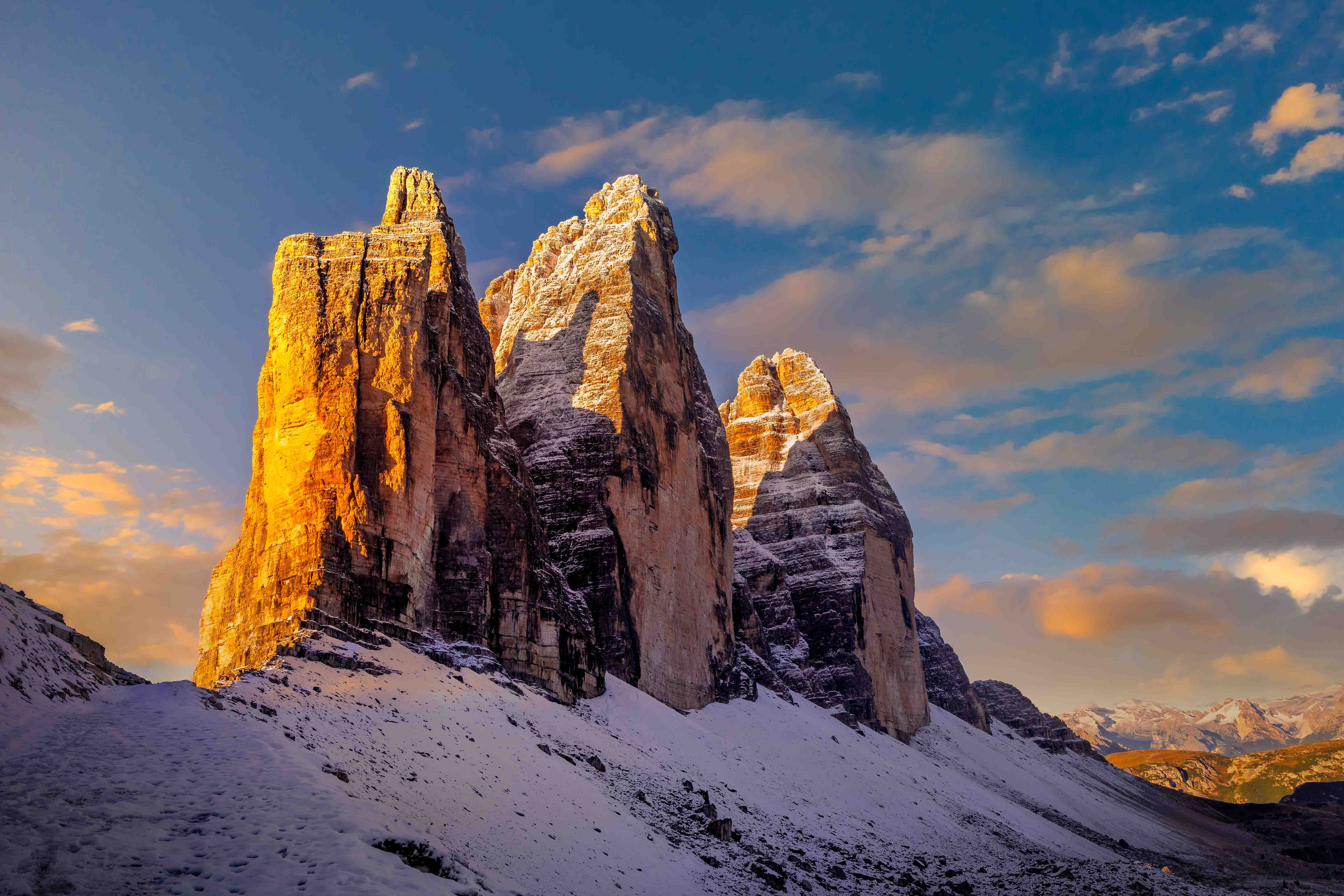 Tre Cime di Lavaredo lit by dawn against a deep-blue sky