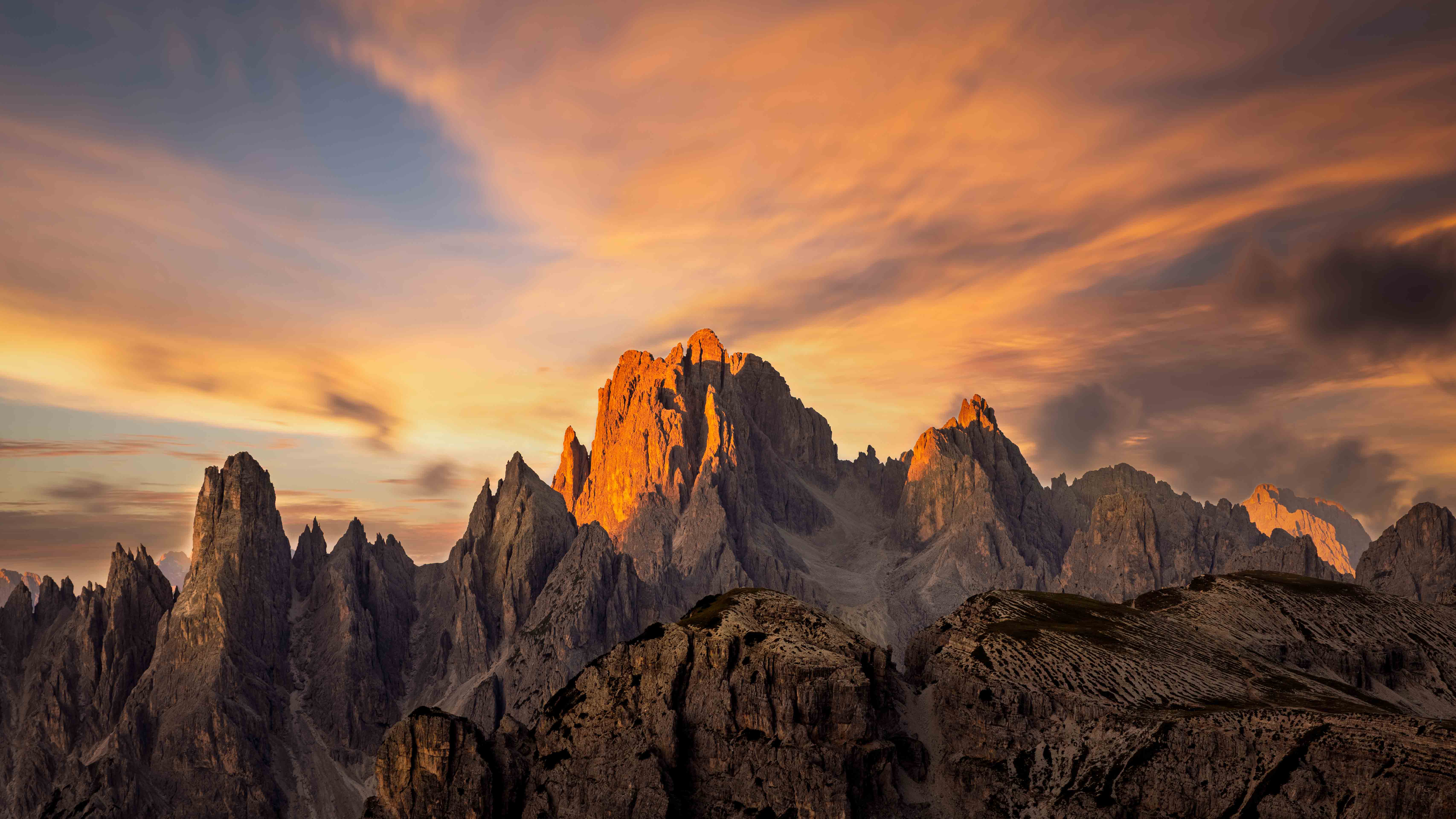 Alpenglow igniting the jagged spires of Cadini di Misurina at sunset with streaked orange clouds overhead