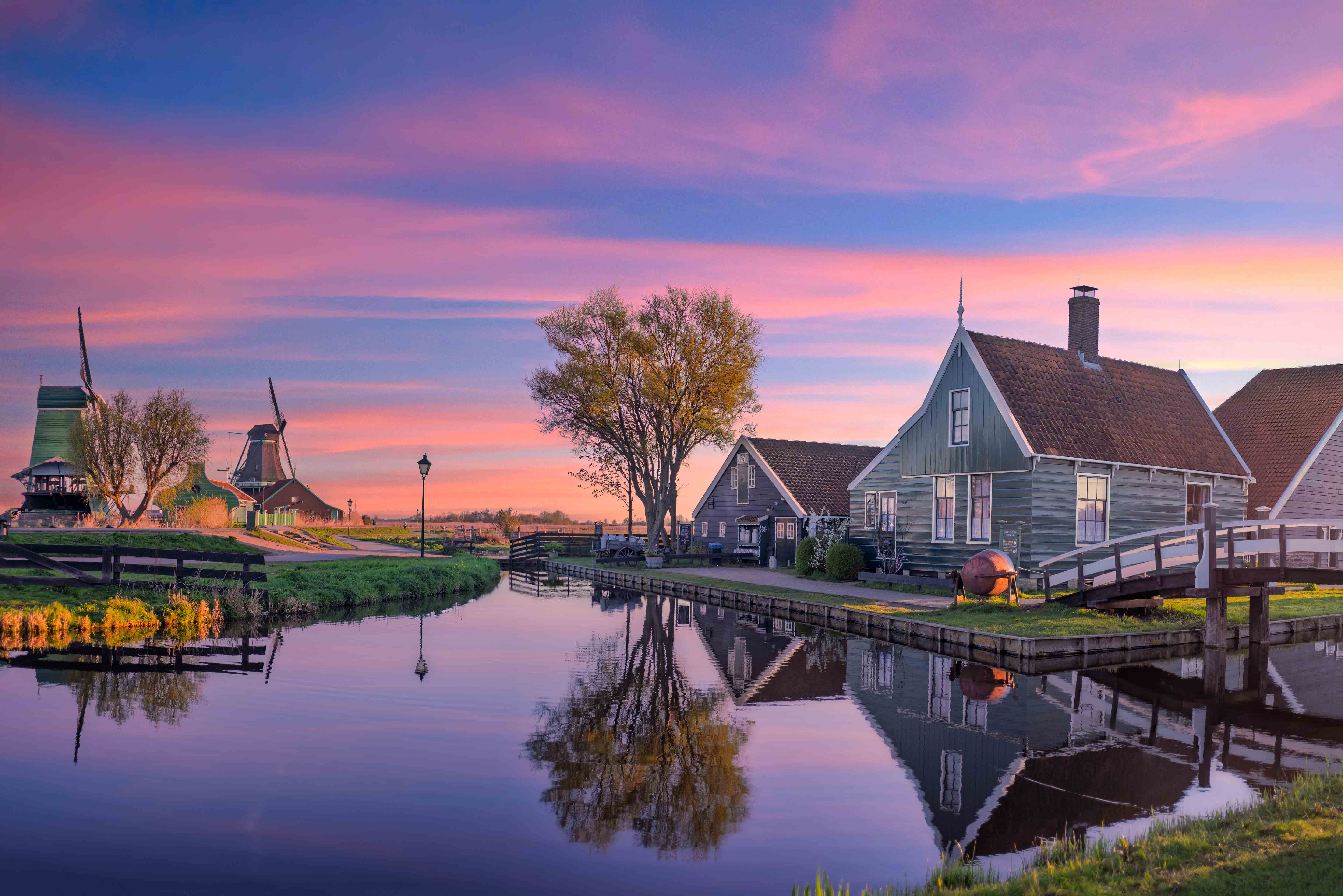 Traditional wooden Dutch windmills along the Zaan river at Zaanse Schans, Netherlands — historic 17th-century industrial architecture