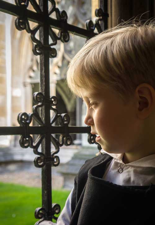 fine art Portrait of a young boy dressed in monks robes looking out over the gardens at Westminster Abbey, London, England